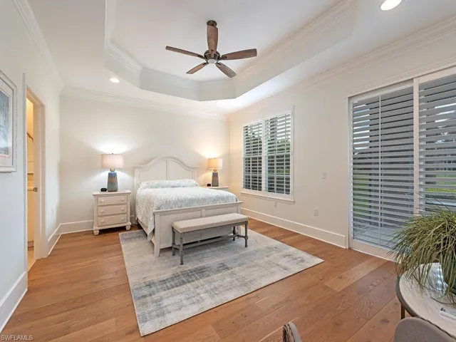 Bedroom featuring hardwood / wood-style floors, access to outside, a raised ceiling, ceiling fan, and ornamental molding