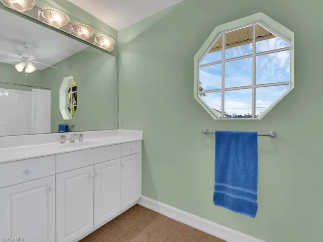 Bathroom with tile patterned floors, ceiling fan, a shower, and vanity