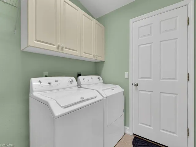 Laundry room featuring cabinets, light tile patterned floors, and separate washer and dryer