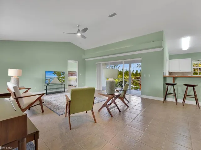 Tiled living room featuring ceiling fan and lofted ceiling