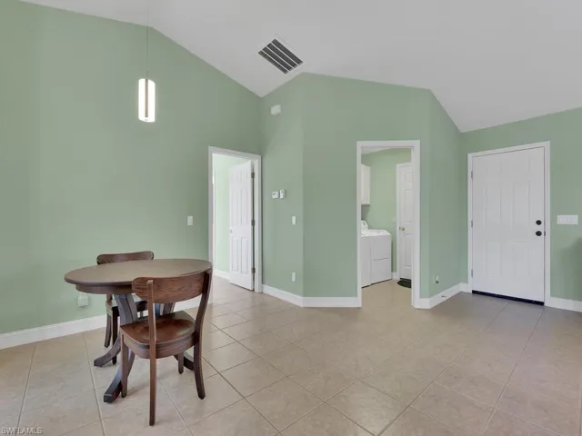 Dining area featuring light tile patterned floors, washer and clothes dryer, and lofted ceiling
