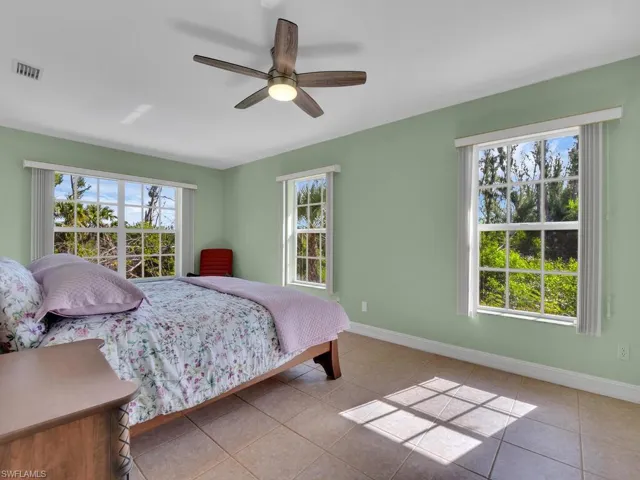 Bedroom featuring ceiling fan, light tile patterned flooring, and multiple windows