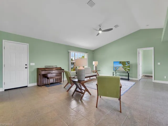 Dining space with ceiling fan, light tile patterned floors, and vaulted ceiling