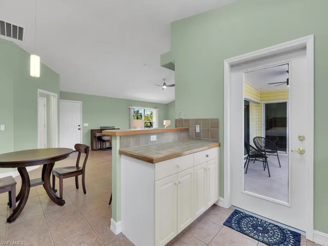 Kitchen featuring white cabinetry, tile counters, backsplash, kitchen peninsula, and decorative light fixtures