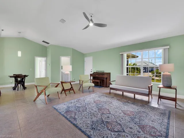 Sitting room featuring ceiling fan, light tile patterned floors, and vaulted ceiling