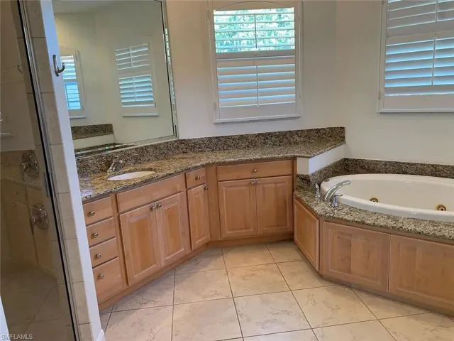 Bathroom with vanity, a shower stall, and a tub with jets