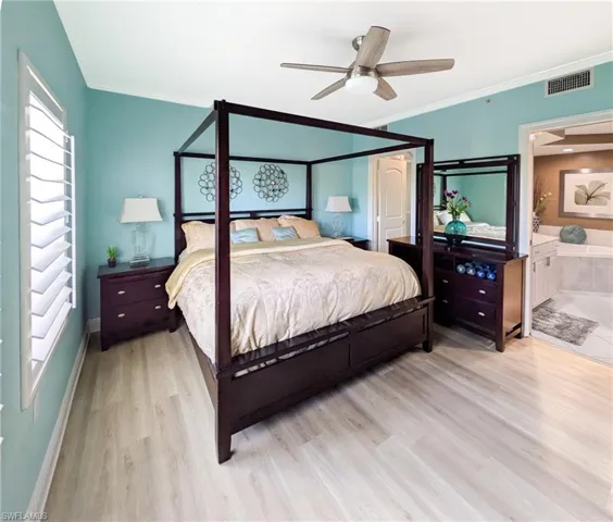 Bedroom with light wood-style floors, a ceiling fan, crown molding, and connected bathroom