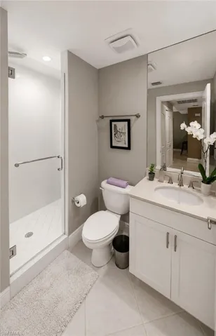 Contemporary bathroom featuring a glass-enclosed shower with white subway tile, a white vanity with recessed panel cabinetry, a light-toned countertop, and tile flooring