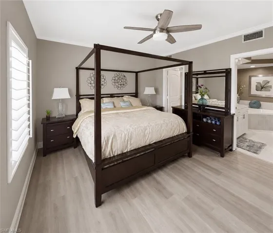 Bedroom featuring light wood-finish flooring, crown molding, a ceiling fan with integrated lighting, and window shutters