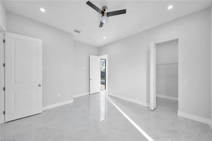 Unfurnished bedroom featuring a spacious closet, a closet, and ceiling fan