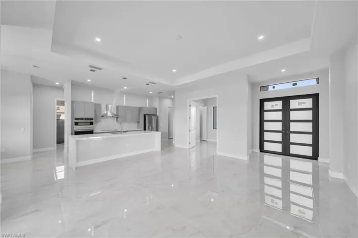 Unfurnished living room featuring french doors, a raised ceiling, and sink