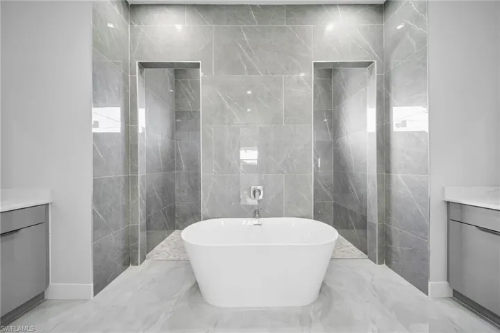 Bathroom with tile walls, vanity, and separate shower and tub