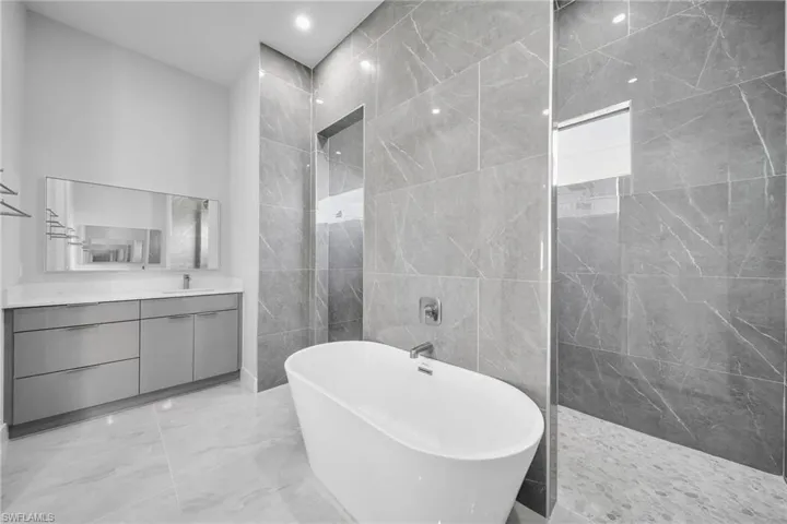 Bathroom with tile walls, shower with separate bathtub, and vanity