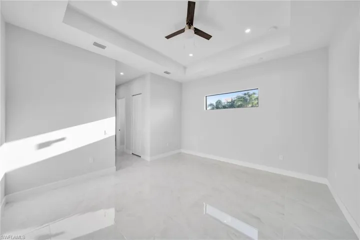 Spare room featuring a raised ceiling and ceiling fan