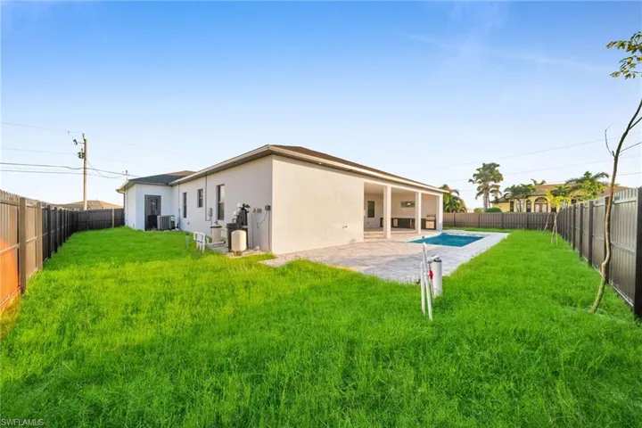 Back of house with a lawn, a patio area, and central air condition unit