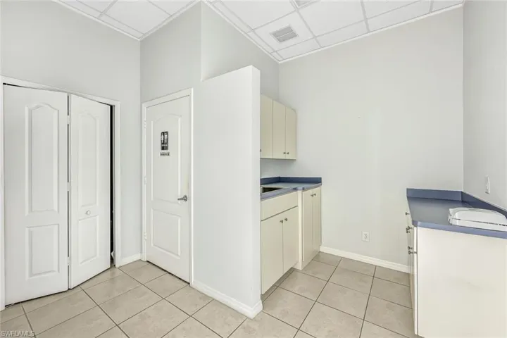 Suite 1 Kitchen featuring a paneled ceiling, light tile patterned floors, and white cabinets