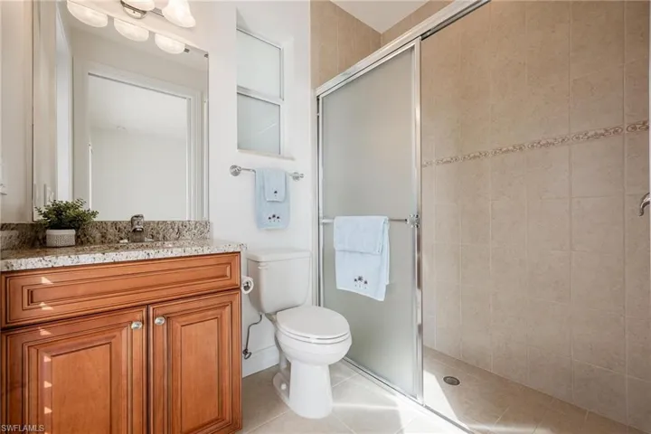 Bathroom featuring tile patterned floors, toilet, an enclosed shower, and vanity