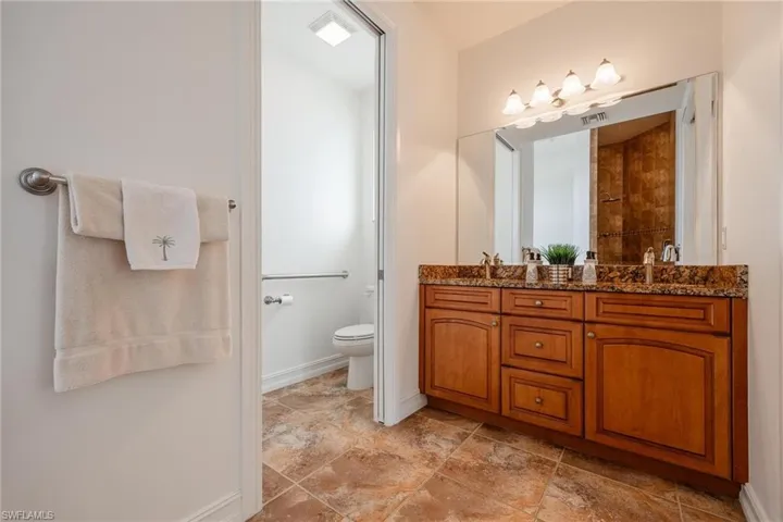 Bathroom with toilet, double vanity, and tile patterned floors