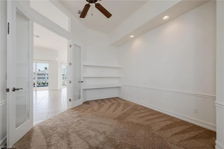 Carpeted spare room with ceiling fan and french doors