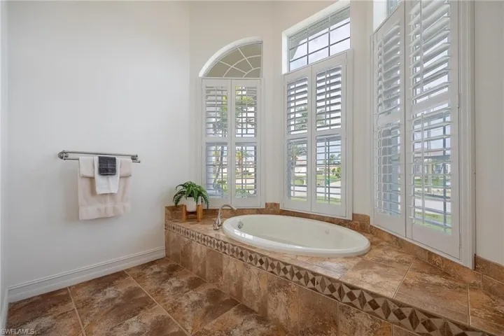 Bathroom with tile patterned floors, plenty of natural light, and tiled bath