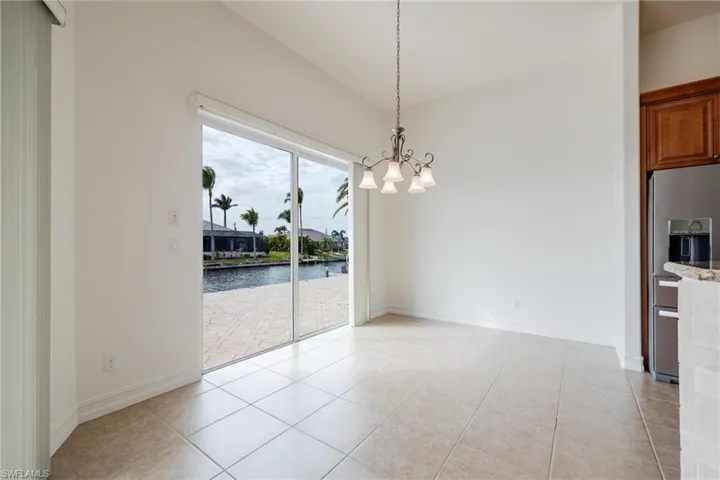 Unfurnished dining area with an inviting chandelier, light tile patterned floors, and a water view
