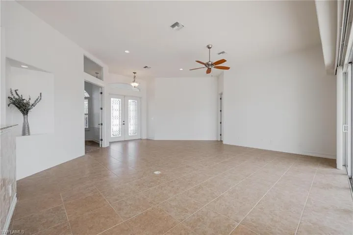 Unfurnished living room with light tile patterned flooring, french doors, and ceiling fan