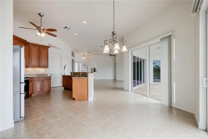 Kitchen featuring tasteful backsplash, white refrigerator, an island with sink, and light tile patterned floors