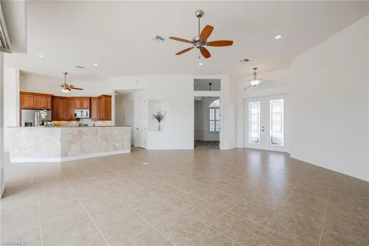 Unfurnished living room with ceiling fan, light tile patterned floors, and french doors