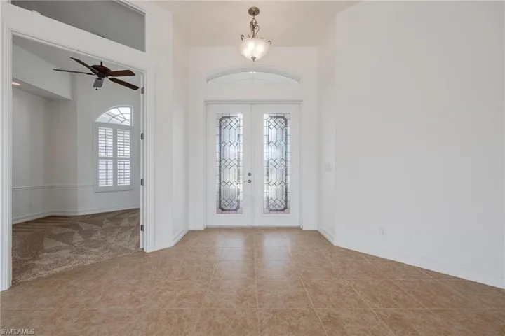 Foyer entrance with ceiling fan, french doors, and tile patterned flooring