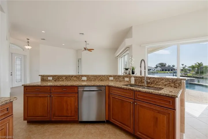 Kitchen with sink, light tile patterned flooring, dishwasher, and a healthy amount of sunlight