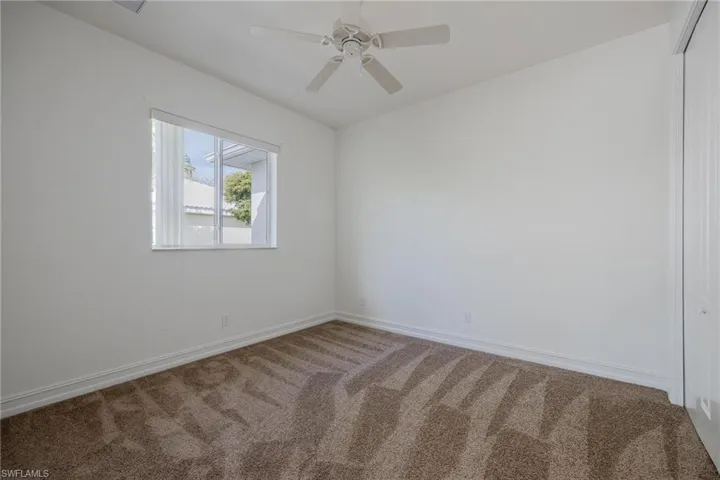 Carpeted empty room featuring ceiling fan