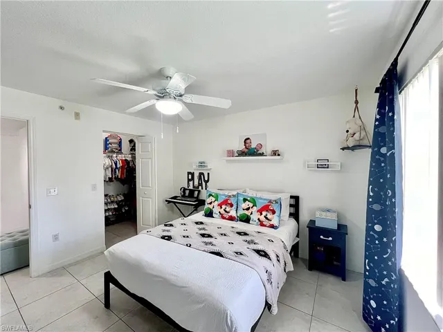 Bedroom with a spacious closet, ceiling fan, a closet, and light tile floors