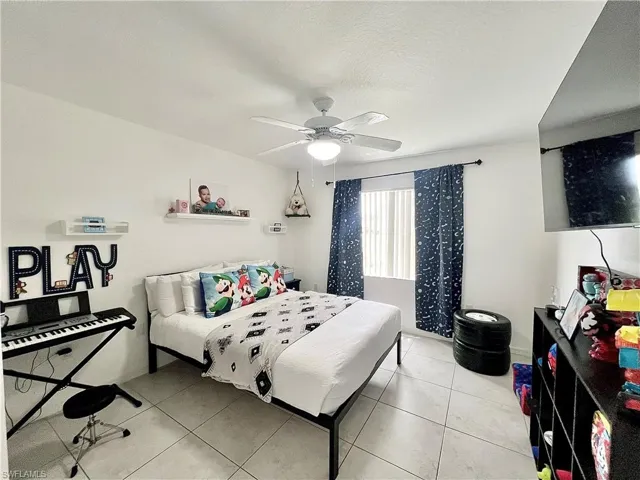 Bedroom with ceiling fan and light tile floors