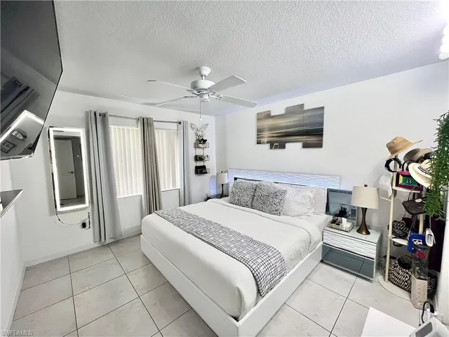 Bedroom featuring a textured ceiling, ceiling fan, and light tile floors