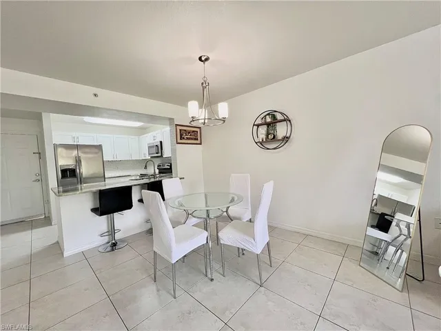 Tiled dining space featuring a notable chandelier and sink