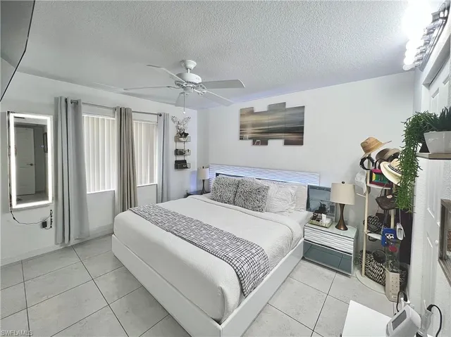 Bedroom featuring a textured ceiling, ceiling fan, and light tile floors