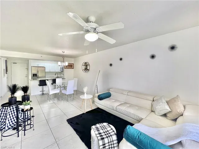 Tiled living room featuring sink and ceiling fan with notable chandelier