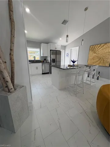 Modern kitchen with white cabinetry, stainless steel appliances, and a dark stone countertop island