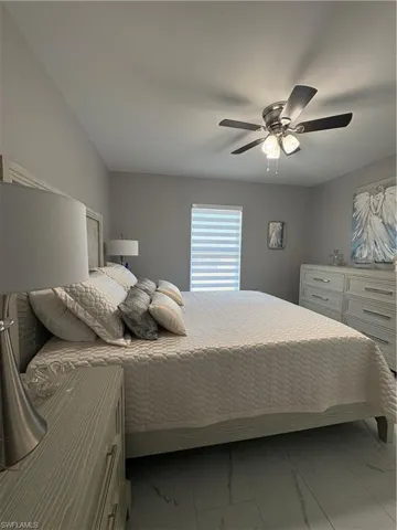 Spacious room featuring light gray walls, a contemporary ceiling fan with integrated lighting, wood-finish flooring, a window with horizontal blinds, and a built-in wall niche