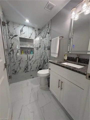 Bathroom featuring a walk-in shower with floor-to-ceiling marble-look tile and a built-in niche