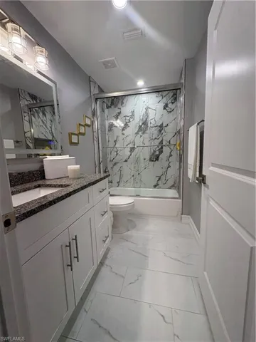 Bathroom featuring a white vanity with dark granite countertop, a rectangular undermount sink, and a multi-bulb vanity light fixture