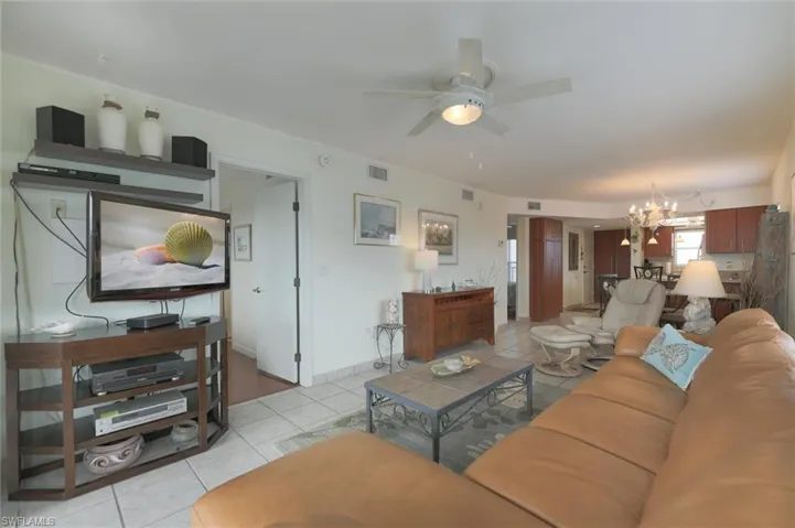 Tiled living room featuring ceiling fan with notable chandelier