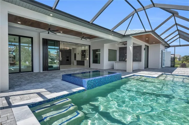 View of swimming pool with ceiling fan, glass enclosure, an in ground hot tub, and a patio area
