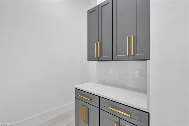 Bar with gray cabinetry, light wood-type flooring, and tasteful backsplash