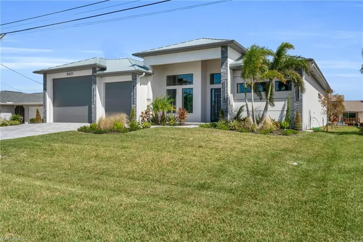 View of front facade featuring a garage and a front lawn