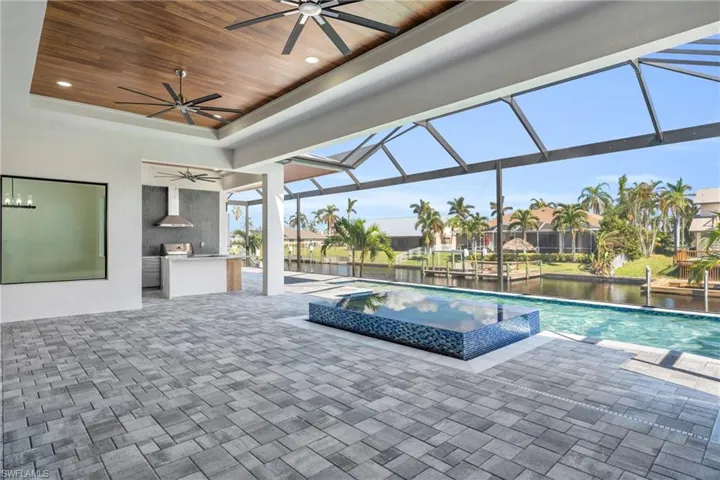 View of swimming pool with a lanai, a water view, ceiling fan, and a patio