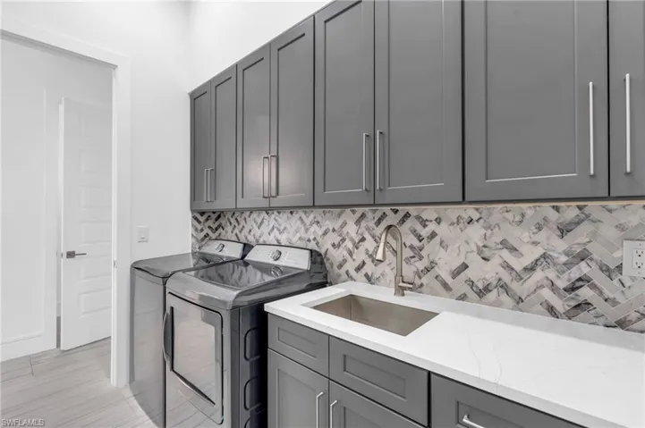 Laundry area with washing machine and dryer, cabinets, and sink