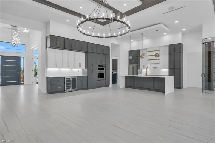 Kitchen featuring a high ceiling, wine cooler, decorative light fixtures, and appliances with stainless steel finishes