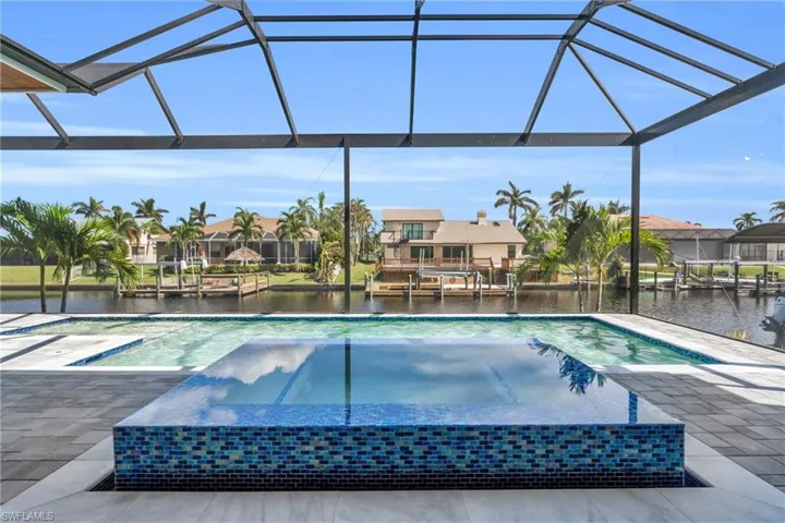 View of pool with a water view, glass enclosure, and a patio area
