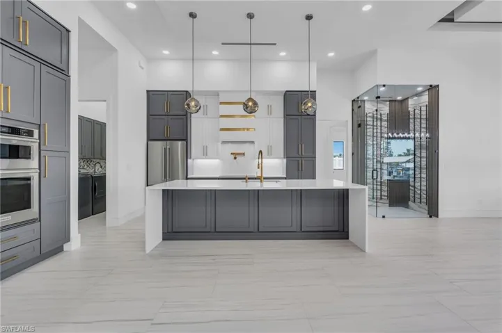 Kitchen with decorative backsplash, hanging light fixtures, gray cabinets, and appliances with stainless steel finishes